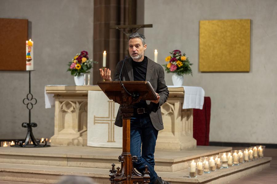 Meron Mendel bei seiner Predigt in der Dreikönigskirche, die Kerzen auf dem Boden stehen für die Menschen, deren Namen verlesen wurden. I Foto: Rolf Oeser
