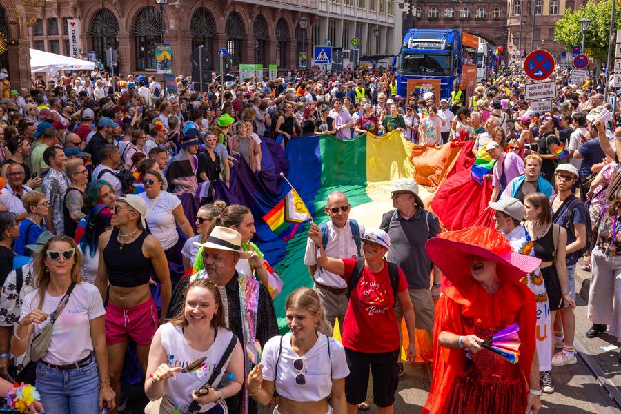 Schon seit vielen Jahren beim CSD dabei - die evangelische Regenbogenfahne. Stadtdekan Holger Kamlah, Bildmitte, Sonnenbrille, gehört zu denen, die sie auf den Weg bringen. I  Foto: Rolf Oeser