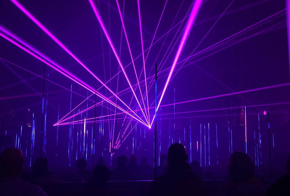 Blaue Laser strahlen in die Höhe des Kirchenschiffs während Lichtstäbe im Publikum zusätzlich Tiefe erzeugen.  |  Foto: Felix Volpp